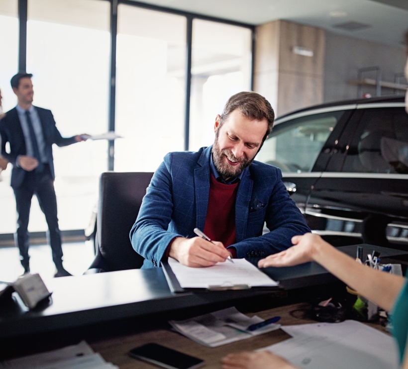 Mężczyzna kupuje/leasinguje nowy samochód i podpisuje umowę