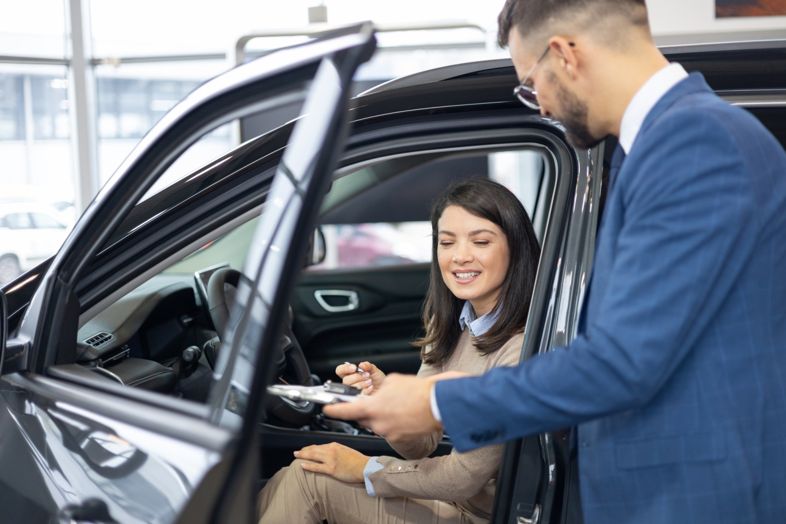 Kobieta podpisuje papiery na nowy samochód w salonie samochodowym