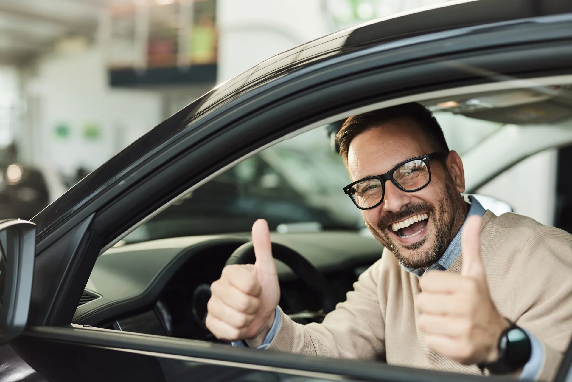 Mężczyzna w samochodzie pokazujący kciuki w górę