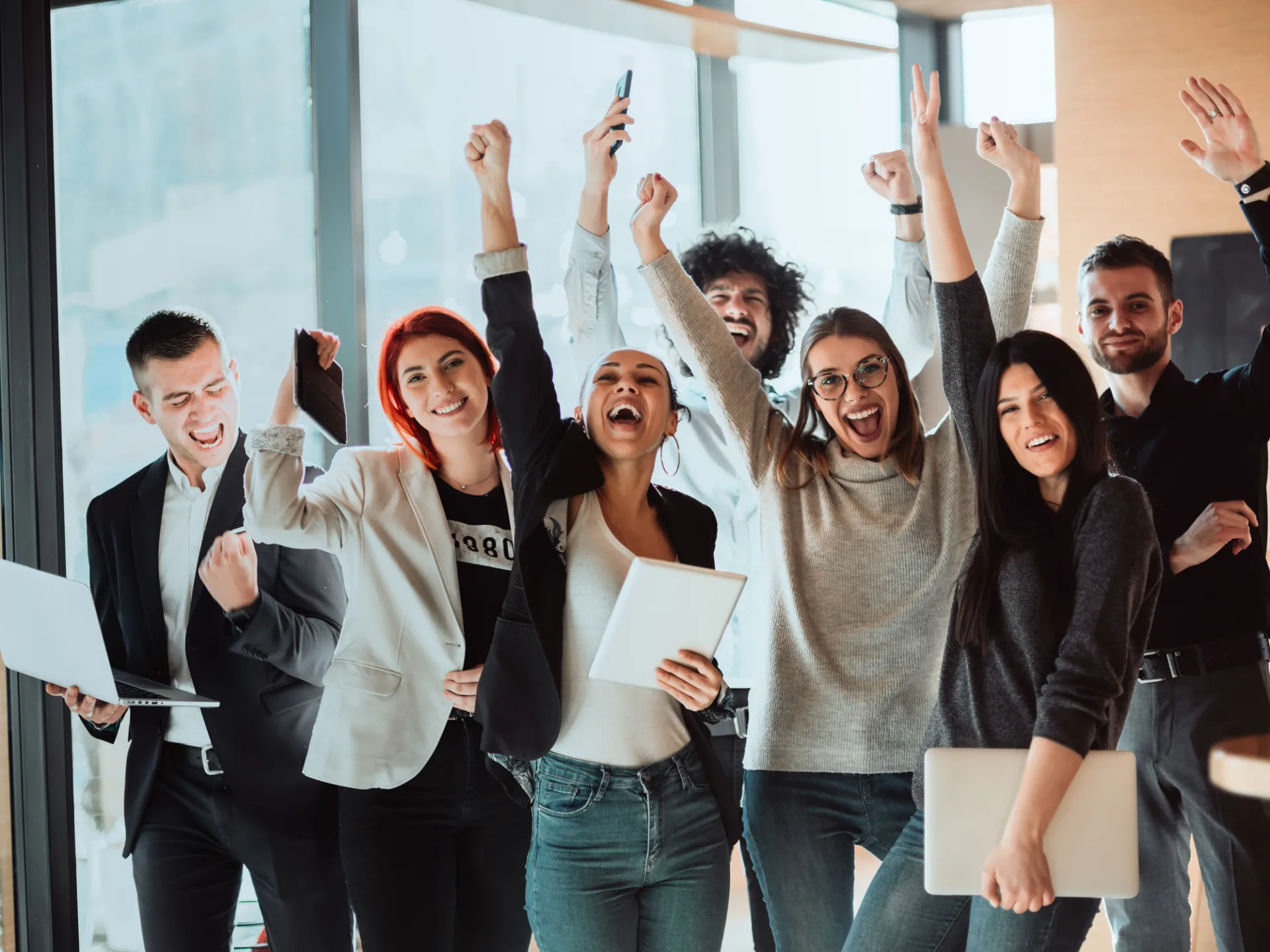 Młodzi uśmiechnięci menedżerowie stojący w nowoczesnym biurze